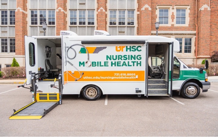 Nursing Mobile Health Trucks parked in front of a brick building.