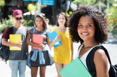 Girl wearing a backpack and holding a binder