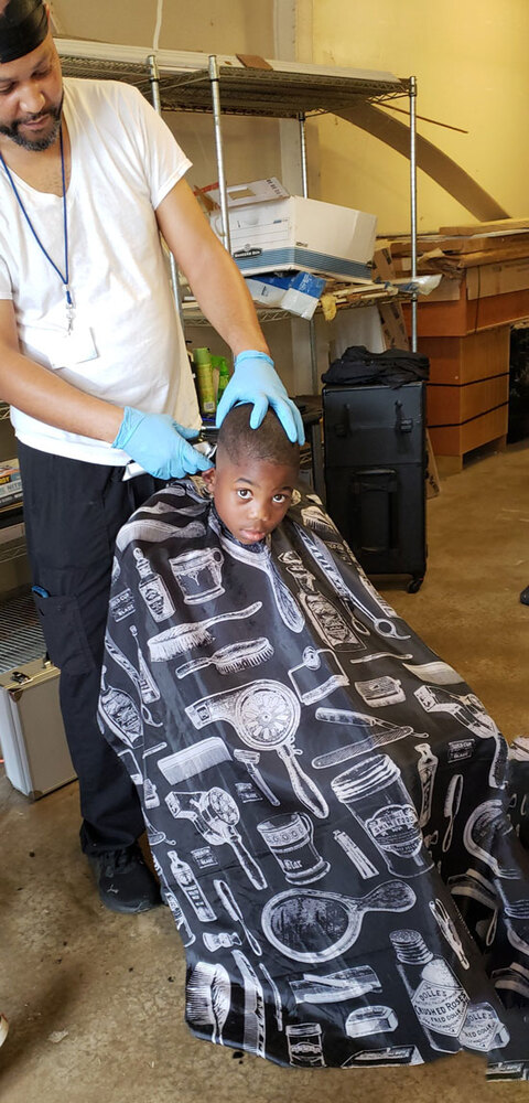 A young boy getting a haircut from a barber.