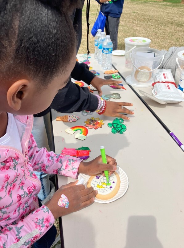 A girl standing at a table doing crafts.