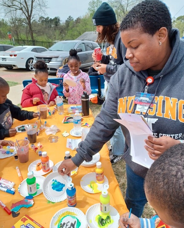 A group of adults and children standing at a table doing crafts.