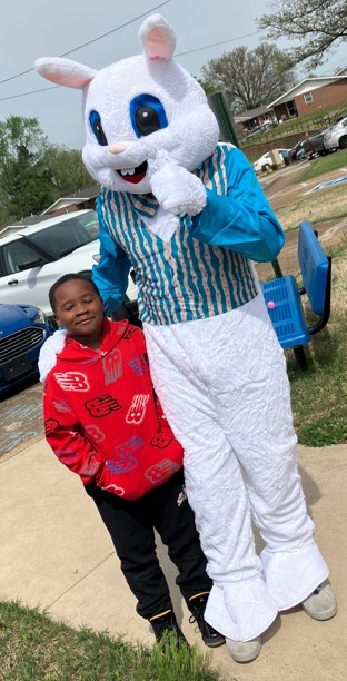 A person in a bunny costume standing outside with a child.