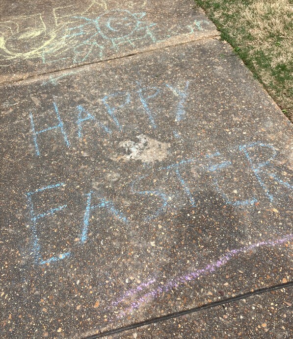 Sidewalk chalk that wrote Happy Easter on the sidewalk.