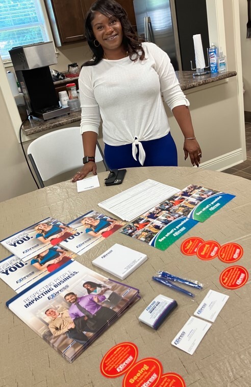 A lady standing behind a table with an assortment of information products for Express Employment Professionals.