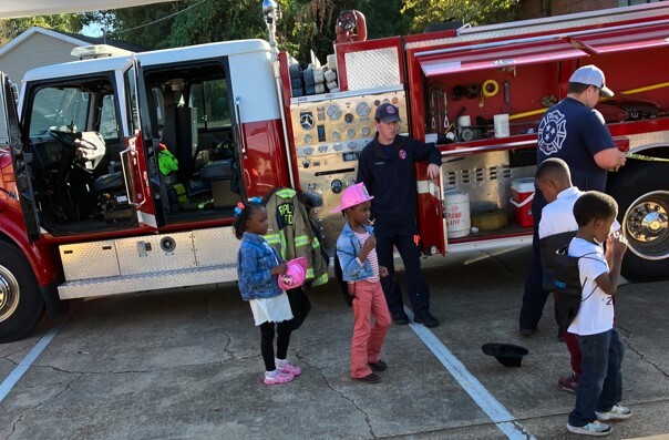 Kids at the fall festival visiting with fire fighters in front of a fire truck.