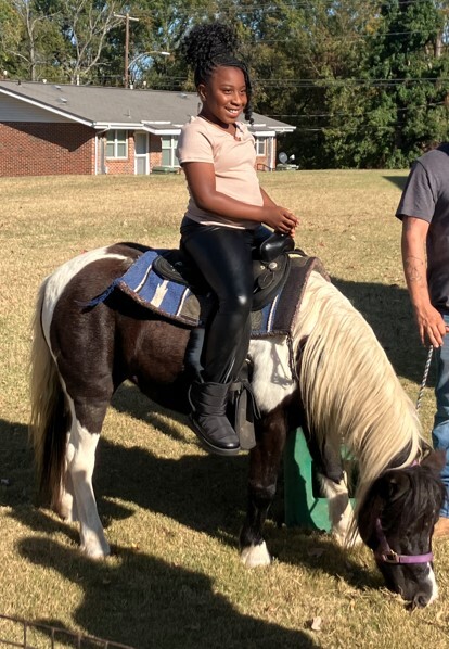 Young lady riding a pony.