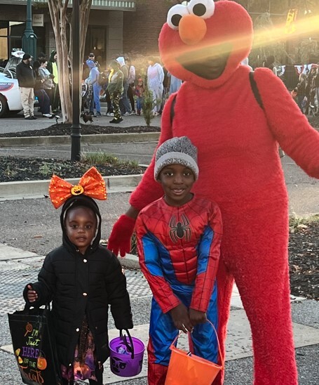 Two children in costume with a giant Elmo.