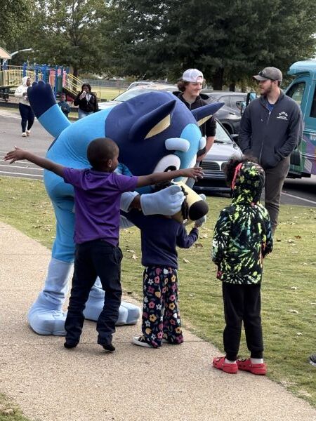 Three little kids hugging Bluey.