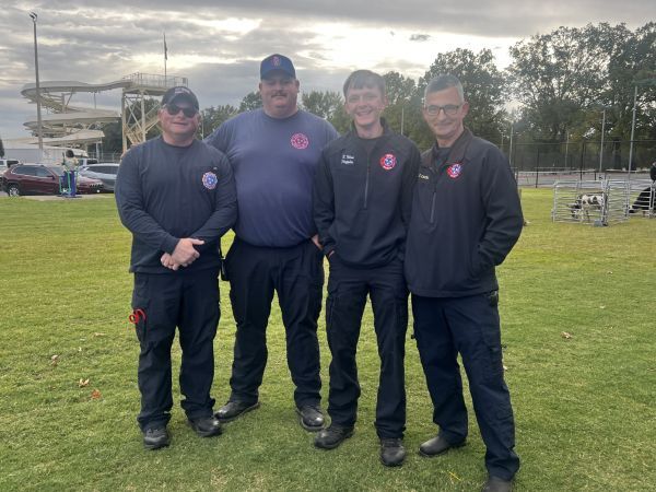 Four Firefighters stand together and smile for a picture.