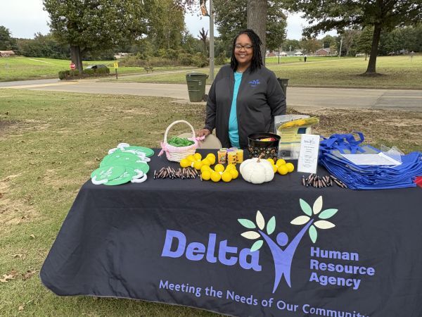 A woman standing behind the Delta Human Resource Agency table. Meeting the Needs of Our Community.