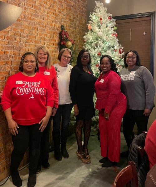 Lineup of women in front of the Christmas tree.