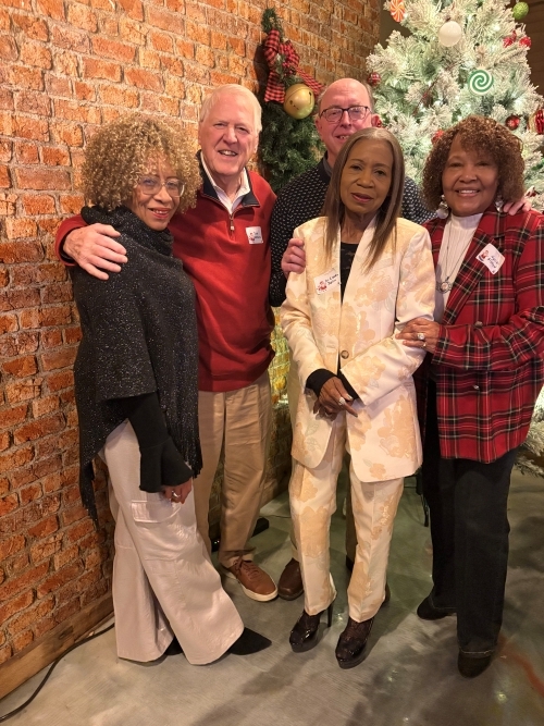 Several people standing in front of the Christmas tree.