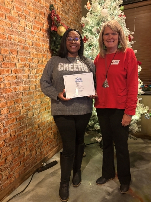 Two ladies standing in front of the Christmas tree.