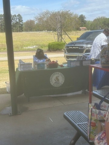 A woman sitting at a table with promotional items on it. 