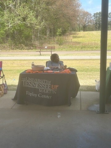 Woman at a University of Tennessee Martin table with items to hand out to people. 