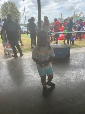 A young child standing and smiling for a photograph. 