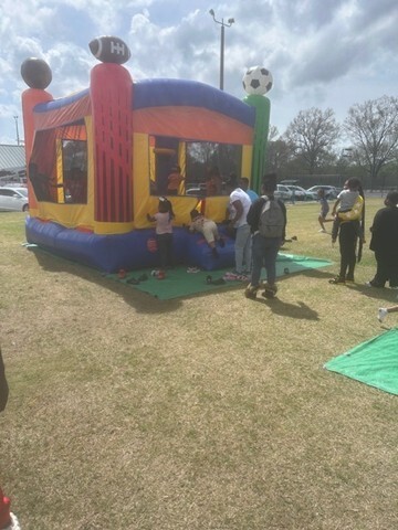 A bounce house with people waiting in line with children. 