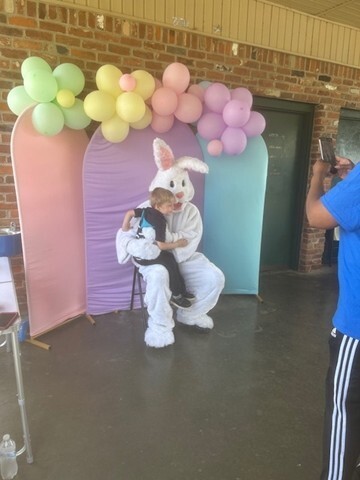 A young boy having his picture taken while sitting on the lap of the Easter Bunny.