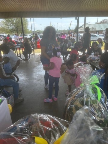 Adults and children mingling with each other under a pavillion. 