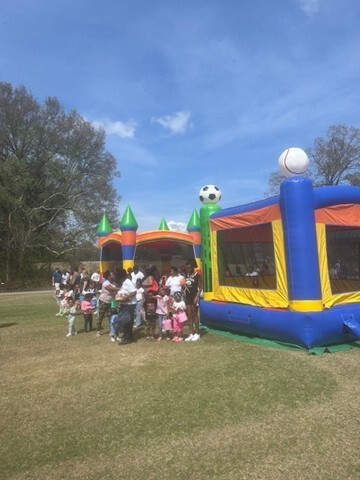 Two bounce houses with children waiting to use them. 