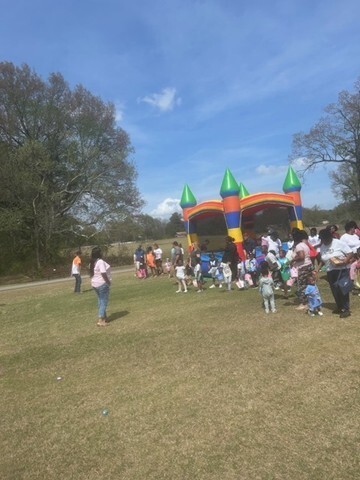 Children and adults watching others use bouncy houses. 