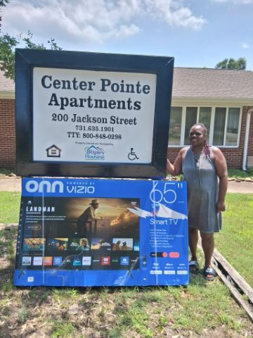 A woman standing next to the Center Pointe Apartments sign with the 65